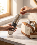 Transparent toothbrush travel case held in hand beside an open toiletry bag on a bathroom counter