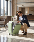 Traveler pulling a laptop from the front-opening aluminum-frame Mixi suitcase in a hotel lobby